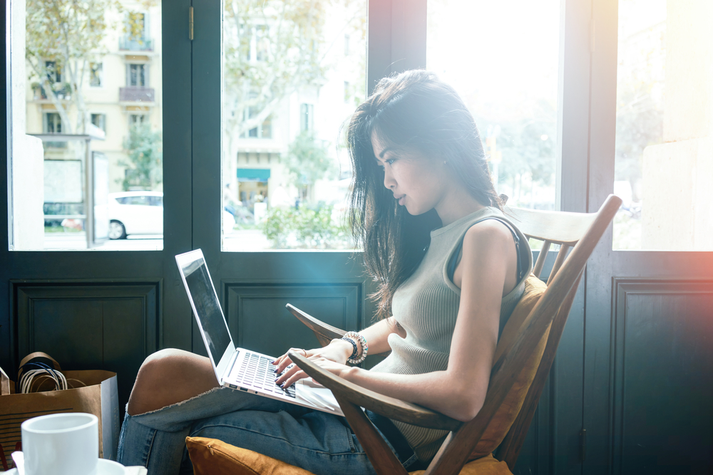 girl blogging laptop window