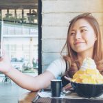 An asian woman using smart phone before eat Bingsu