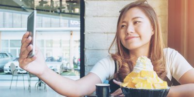 An asian woman using smart phone before eat Bingsu