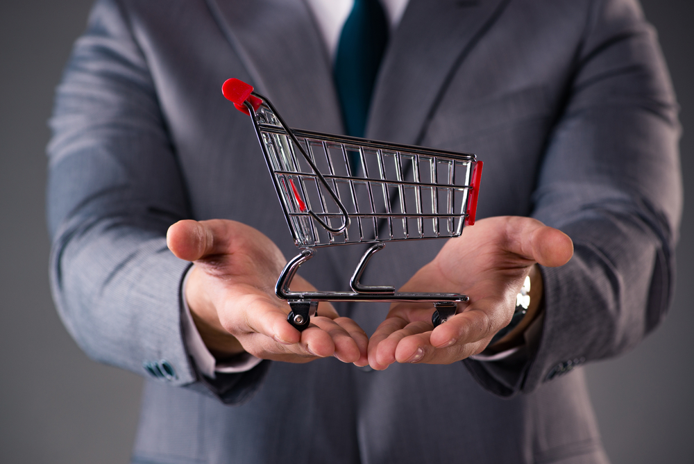Businessman holding shopping cart in business concept