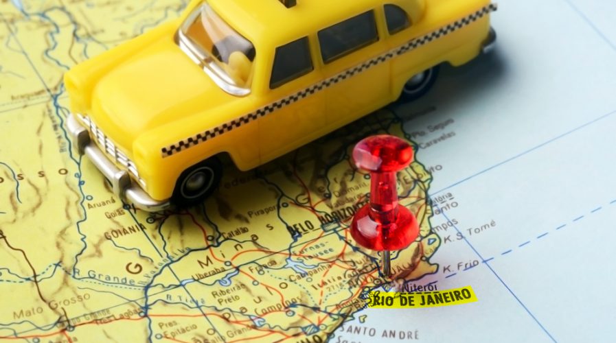 Close-up of a red pushpin on a map of Rio de Janeiro and a taxi car