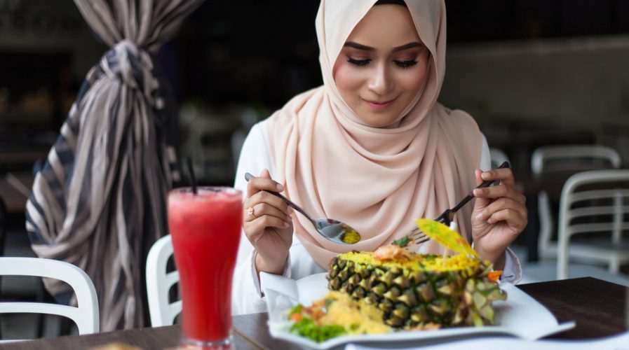 malay woman eating at cafe with juices and food