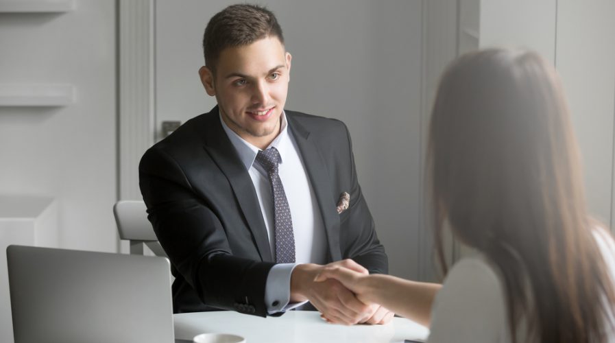 businessman and businesswoman handshaking over the office desk