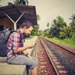 Young traveler with mobile phone on the railway