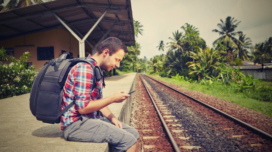 Young traveler with mobile phone on the railway
