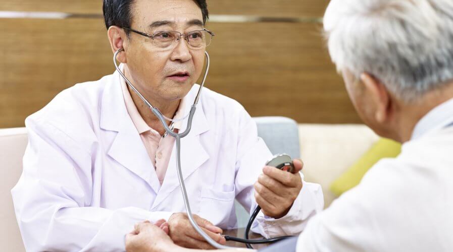 a doctor checking the blood pressure of an elderly man