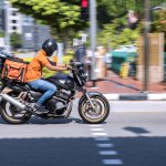 A food delivery worker was riding a motorbike on a street