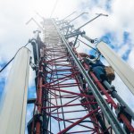 a worker climbing up a communications tower