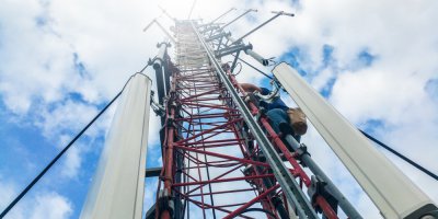 a worker climbing up a communications tower