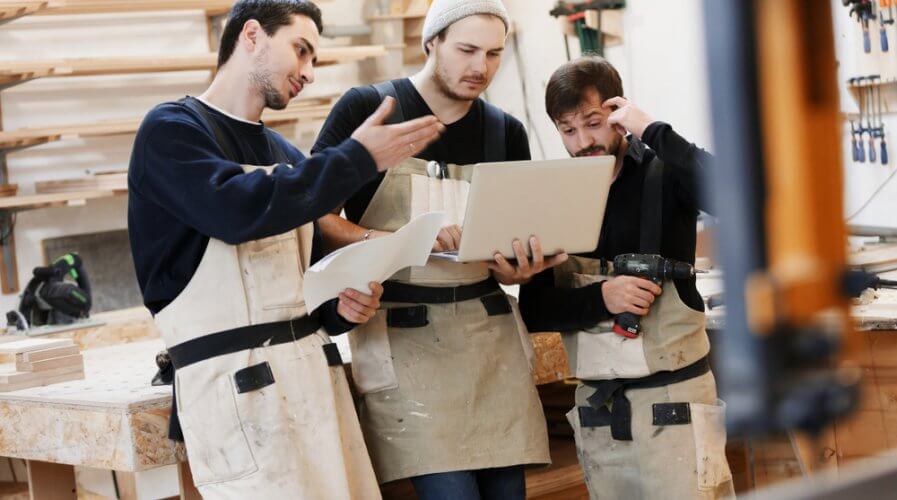 a small carpentry team looking at a laptop