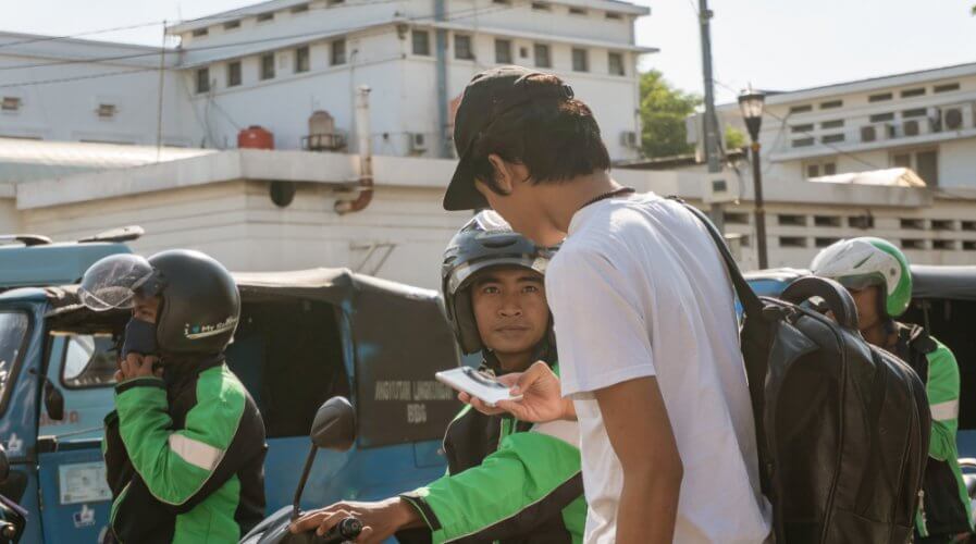 a go jek user getting picked up by a rider