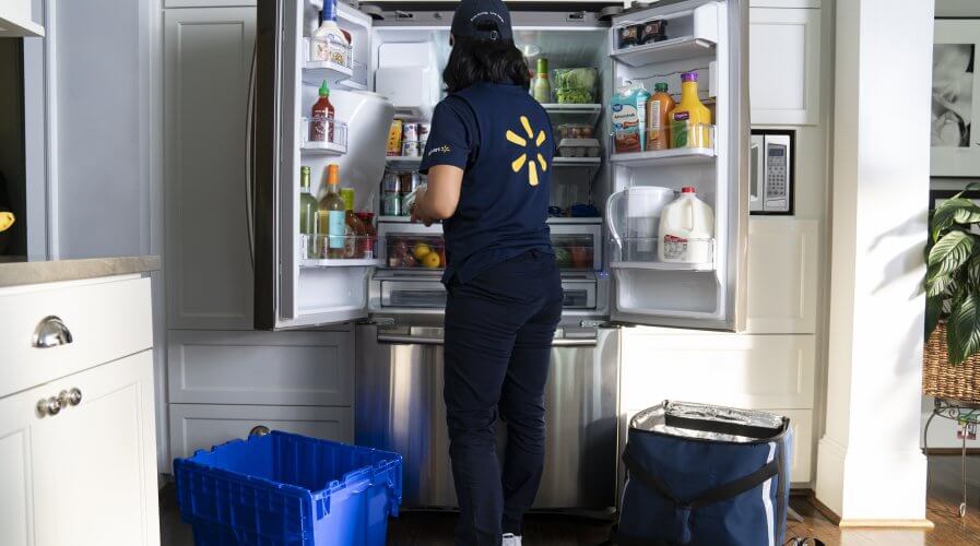 Walmart associate stocking a fridge with InHome Delivery. Source: Walmart