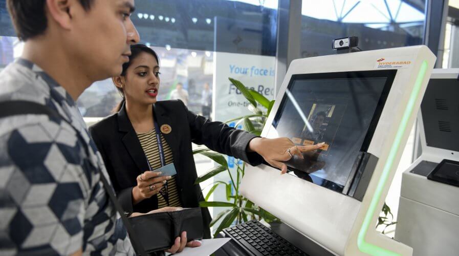 An airport staff member shows a passenger how to register his personal details at a facial recognition counter. Source: AFP