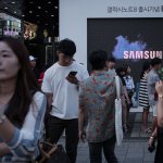 Pedestrians passing a Samsung promotional event outside a store in Seoul.