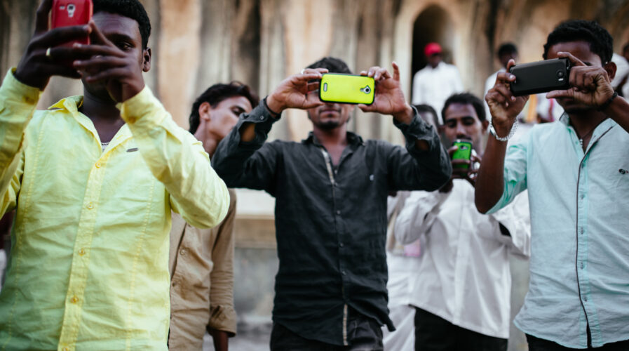 Tourists in India take pictures with smartphones.
