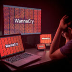 Young male frustrated, confused and headache by WannaCry ransomware attack on desktop screen, notebook and smartphone, cyber attack internet security concept