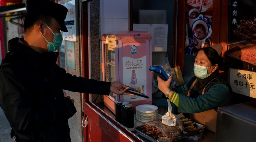 A Chinese customer makes an electronic payment on his smartphone in Beijing, China (Photo by NICOLAS ASFOURI / AFP)