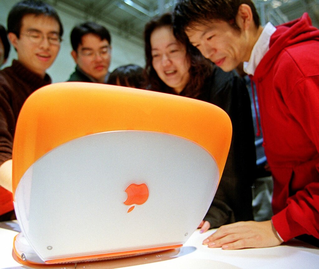 Japanese youths smile as they look at the new iBook from US computer maker Apple Computer Inc,. at a department store in Tokyo 16 October 1999. The firm started selling iBook and iMac DV in Japan today at a price of 198,000 yen (1,860 dollars). AFP PHOTO/Toru YAMANAKA (Photo by TORU YAMANAKA / AFP)