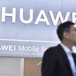 A visitor stands next to the Huawei stand at the Mobile World Congress (MWC). (Photo by Pau BARRENA/AFP).